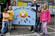 Kommunionkinder mit Plakat auf dem Kirchplatz