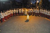 Priester und Ministranten warten am Feuer